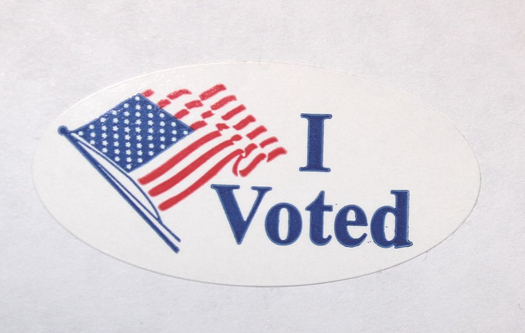 Photo is of an "I Voted" sticker with an American flag.